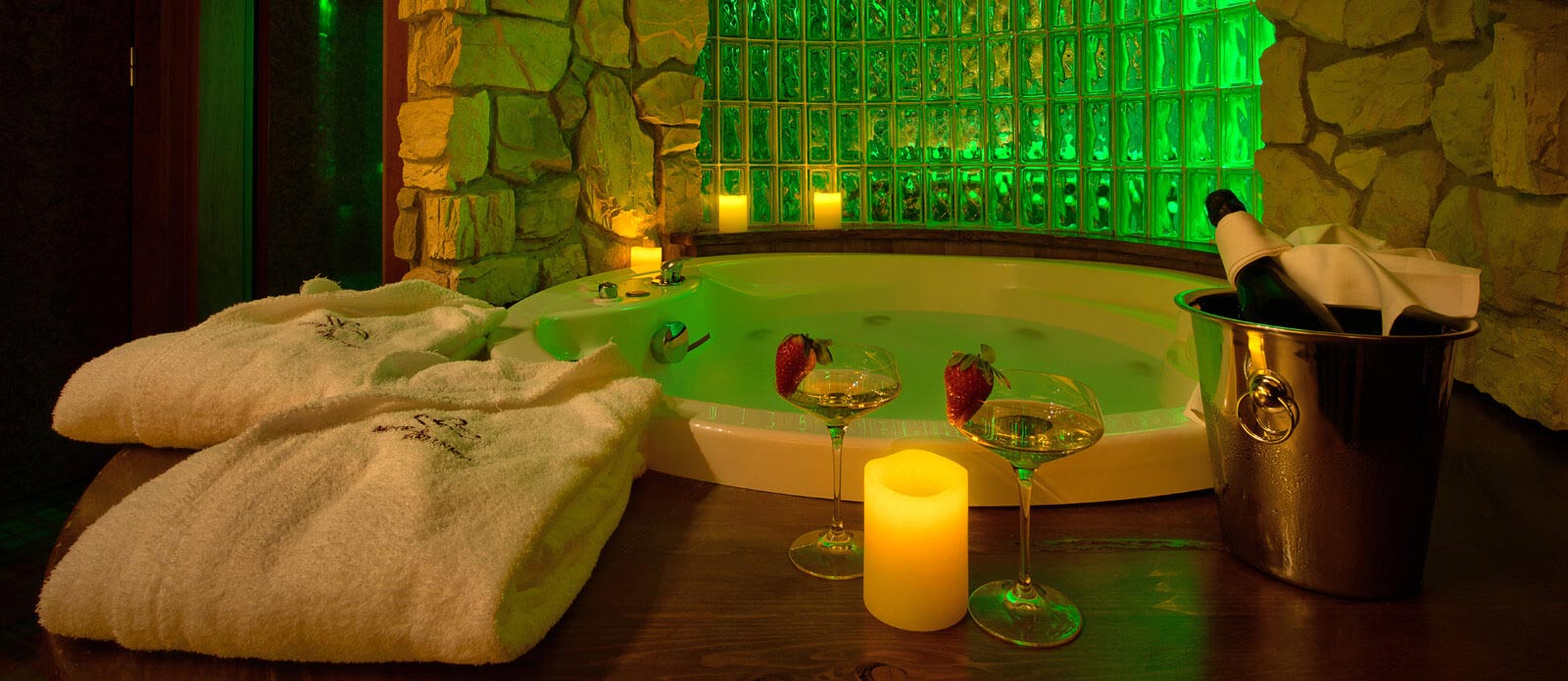 Motel K Senior Suite Baita Motel K Senior Suite Baita vista su vasca idromassaggio rotonda per 2 persone, con servizio candele in suite, bottiglia di champagne in secchiello del ghiaccio e 2 bicchieri appoggiati a bordo vasca camera a tema Chalet di montagna