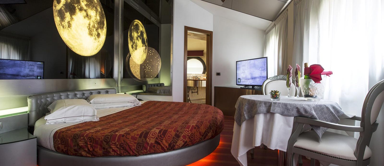 Motel K Senior Suite Luna vista sul letto rotondo con dietro coreografia della Luna piena, specchio a soffitto TV davanti al letto camera a tema chiaro di Luna
