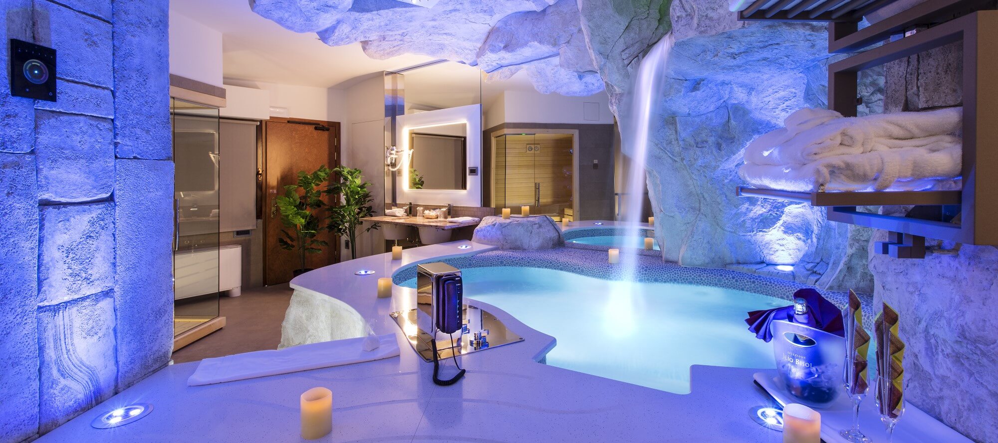 Motel K Wellness Suite Tulum vista sulla mini piscina con idromassaggio, cascata e cromoterapia, sullo specchio di fianco alla mini piscina si intravede la sauna privata della suite, camera a tema antica civiltà azteca